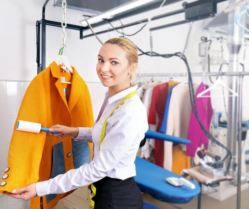 Woman holding a yellow coat in the dry cleaning area