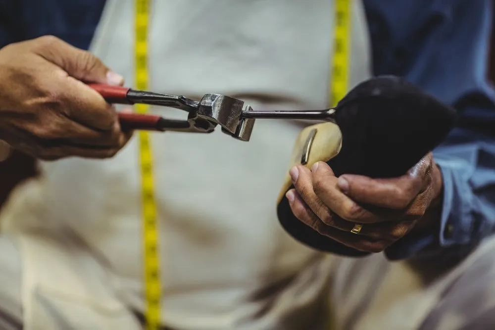 Close-up of a heel tip being replaced on a black high-heel shoe