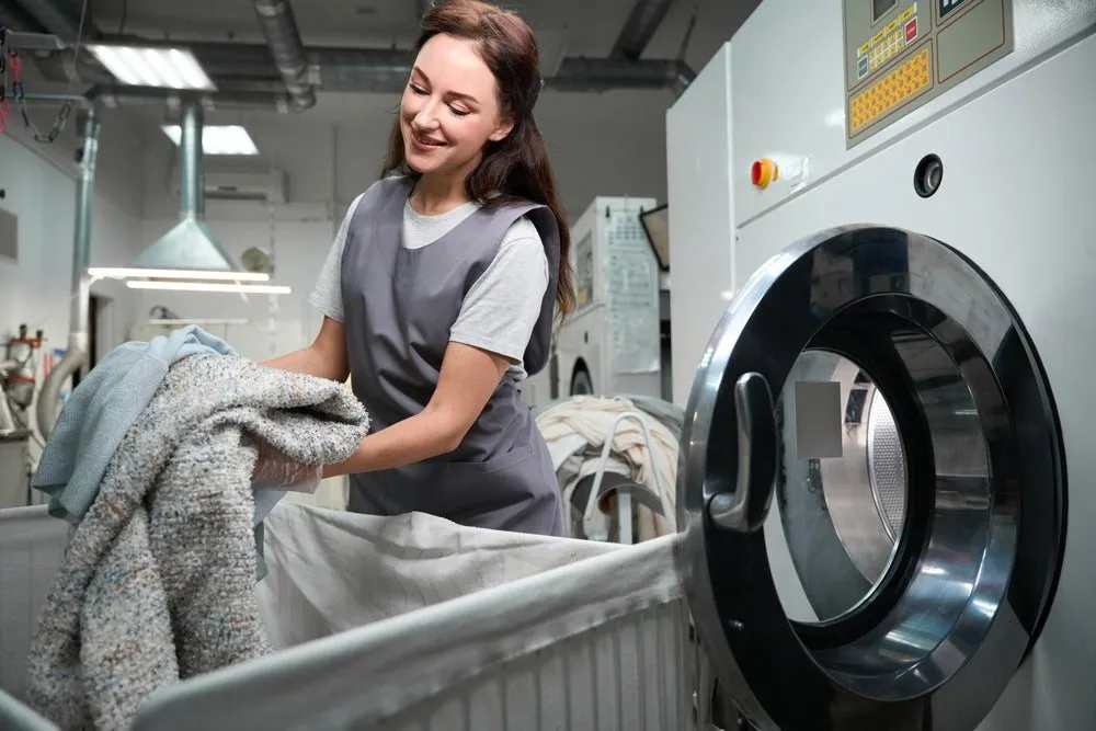Woman in the WhizzFix laundry room with washing machines and clothes