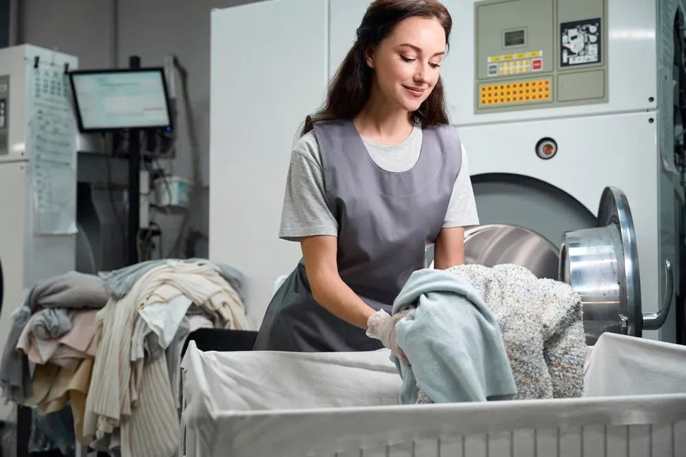 Staff member loading laundry into an industrial washing machine at WhizzFix in St Julian's