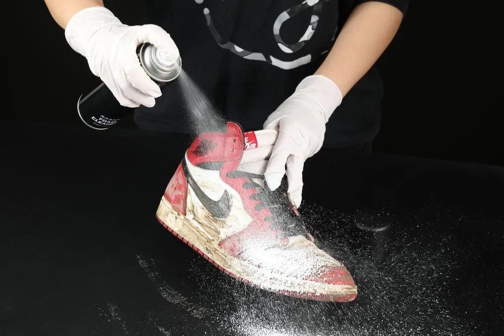 Gloved hands cleaning a red Nike high-top sneaker on a black table at WhizzFix