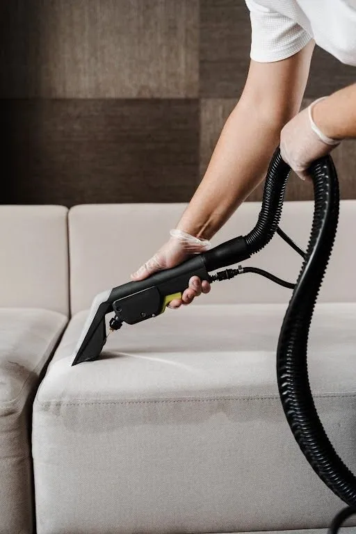 Beige sofa being sanitised with a steamer